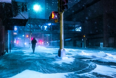 穿着黑色夹克的人在夜间站在积雪覆盖的道路上